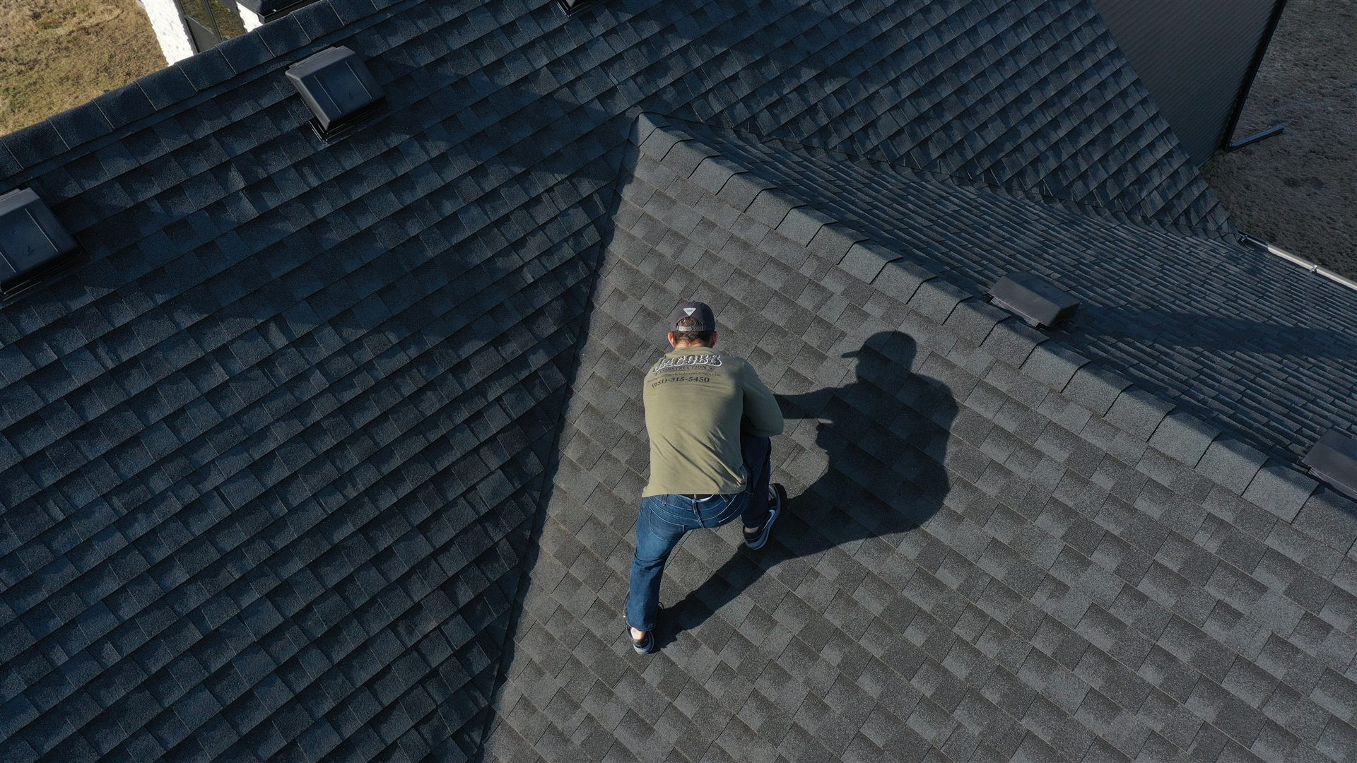 Tom Jacobs, owner of Jacobs Construction, inspecting a newly shingled roof ridge