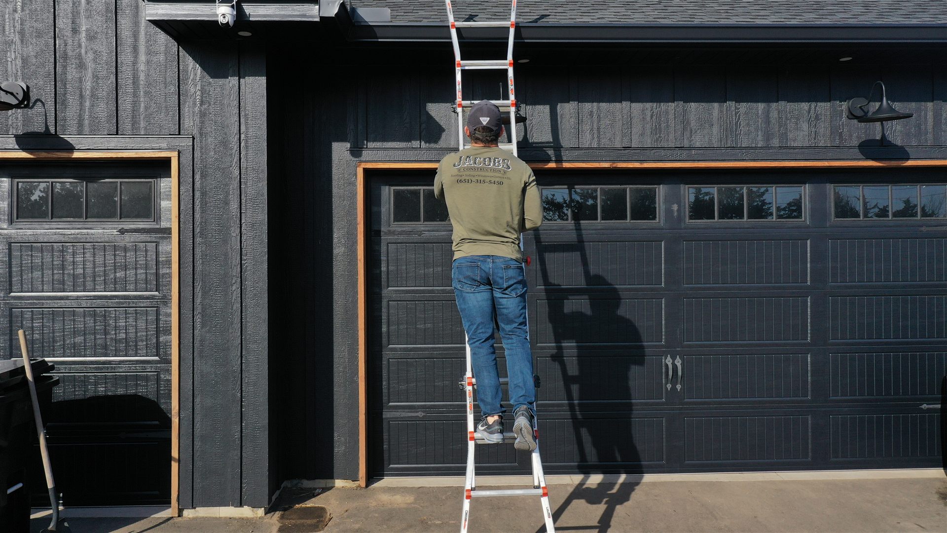 Tom Jacobs on a ladder at a job site, Jacobs Construction shirt visible